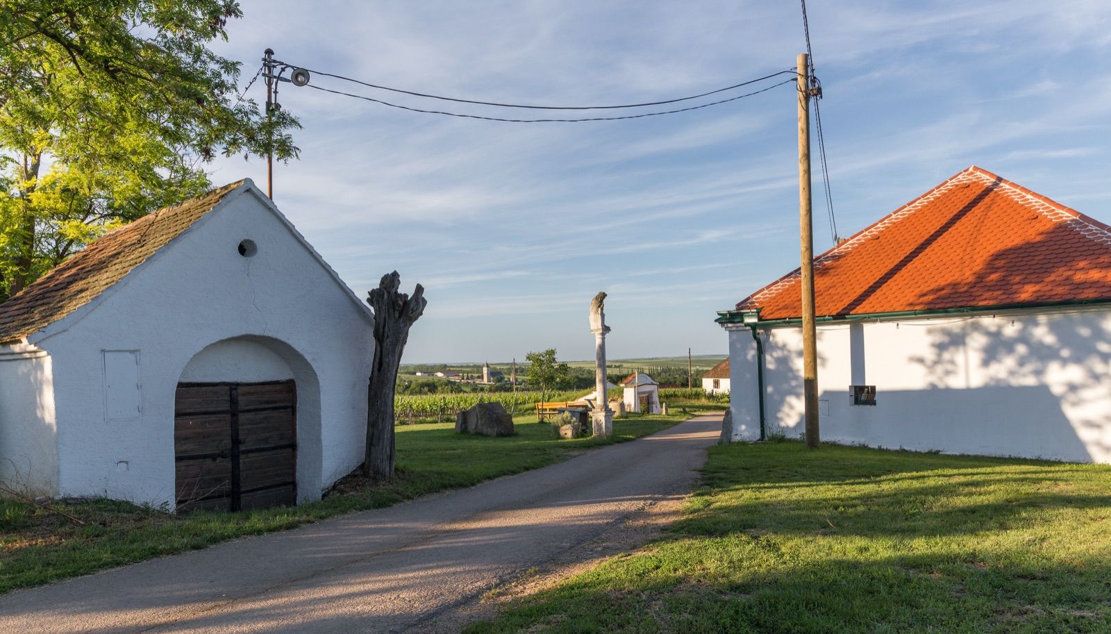 Presshäuser und Wegkreuz in der Kellergasse Maulavern bei Zellerndorf, mit Blick in die Weinviertler Rebenlandschaft entlang der Route.