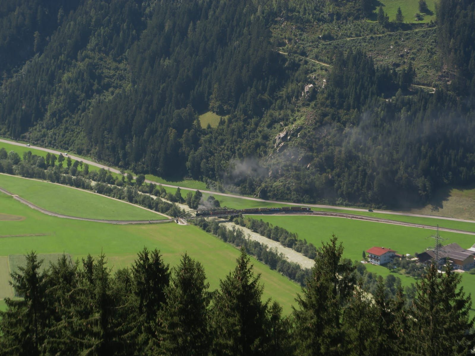 Der Dampfzug der schmalspurigen Zillertalbahn quert die Talwiesen - die Bahn begleitet den Radweg und nimmt Räder mit.